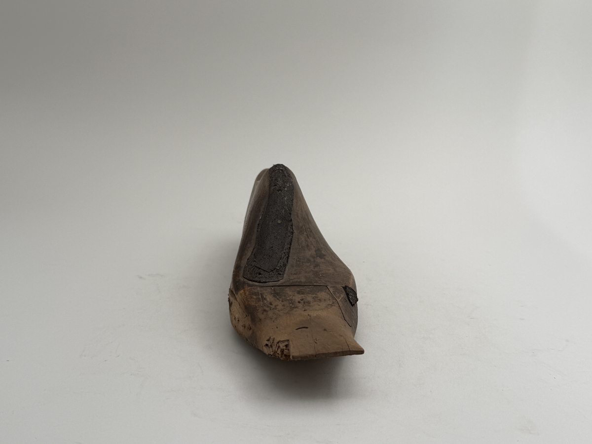 Skoläst för herrskor. Vänsterfot.
Gjord i björkträ med läderbitar fastpliggade på vristdelen. 
 