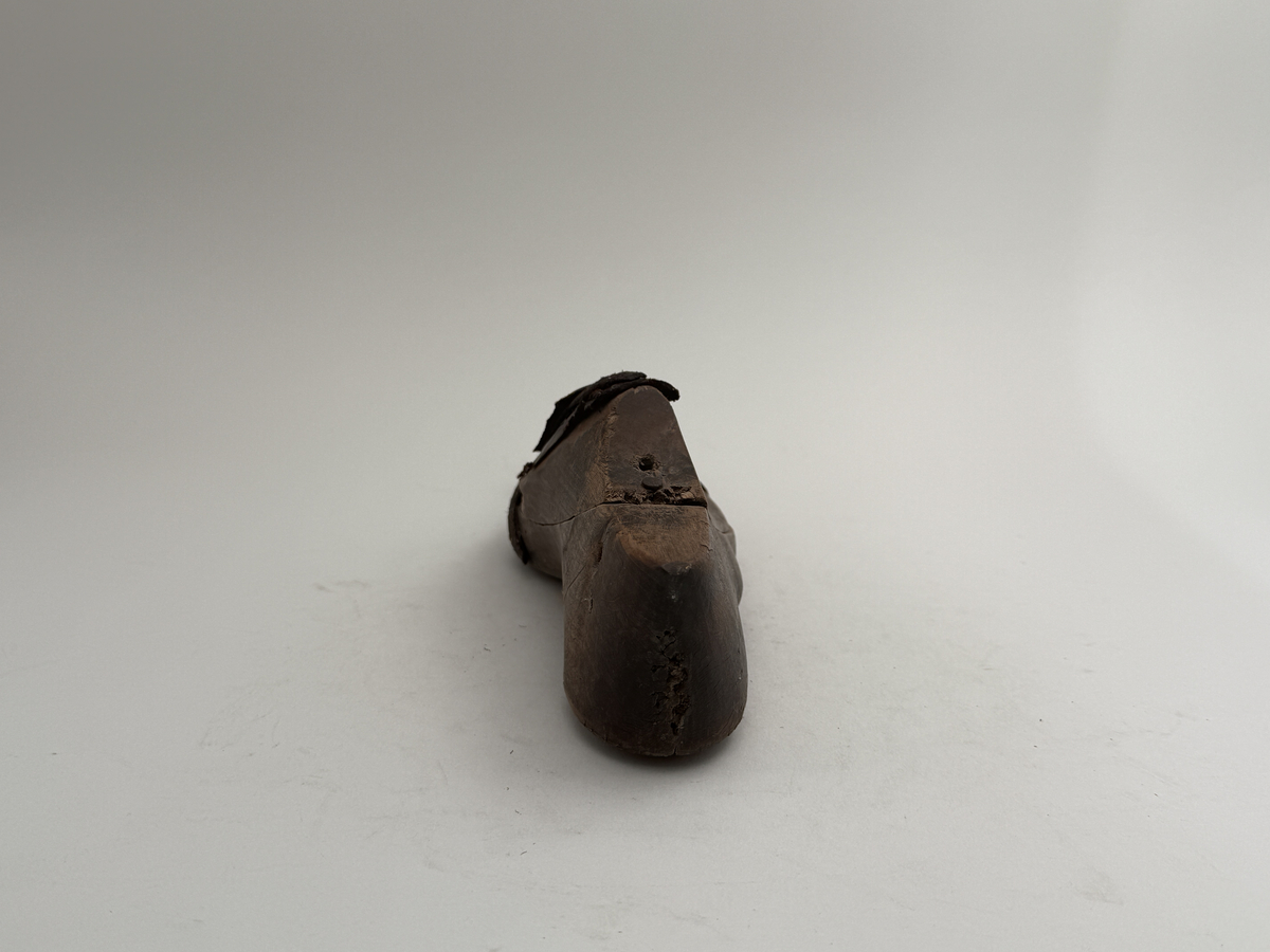 Skoläst för herrskor. Högerfot.
Gjord i björkträ med läderbitar fastpliggade på vristdelen. Tåhällen klädd med lärft. 
 