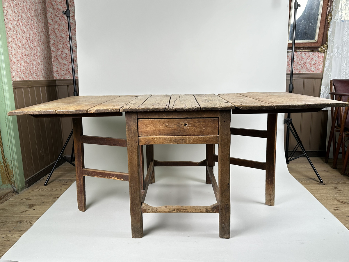 Slagbord i furu. Bordstativ vari två utfällbara stöd för klaffarna fälls ut. Bordskiva samt klaffar av breda plankor. Lådor i sargen på sidorna utan klaffar. 