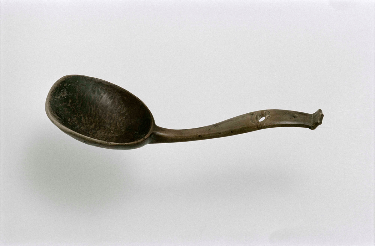 Stor slev av omålad björk, böjt skaft med snidat avslut likt en krona, upphängningshål. Inristat på skafets baksida "PS 29 .
Användes vid tillagning av bröllopsmat.