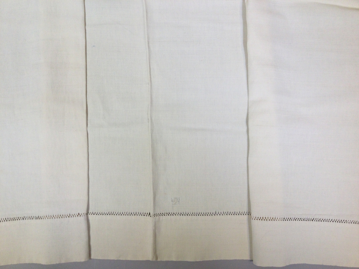 Överlakan i kraftig tuskaftad bomullsväv. Två våder, handsytt. Hålsömsbård 8,5 cm från överkant. Likadant som SKAFOR.0017095