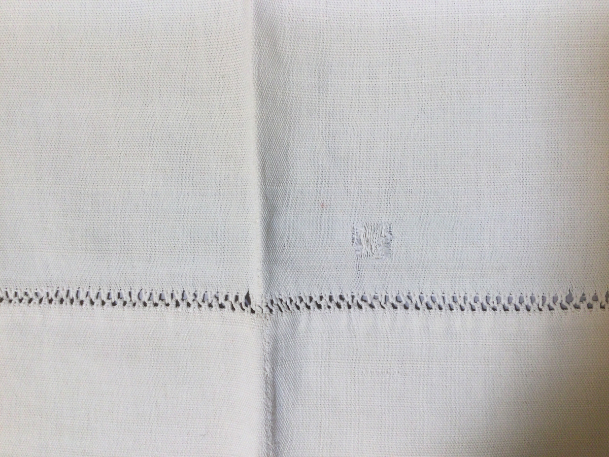 Överlakan i kraftig tuskaftad bomullsväv. Två våder, handsytt. Hålsömsbård 8,5 cm från överkant. Likadant som SKAFOR.0017095