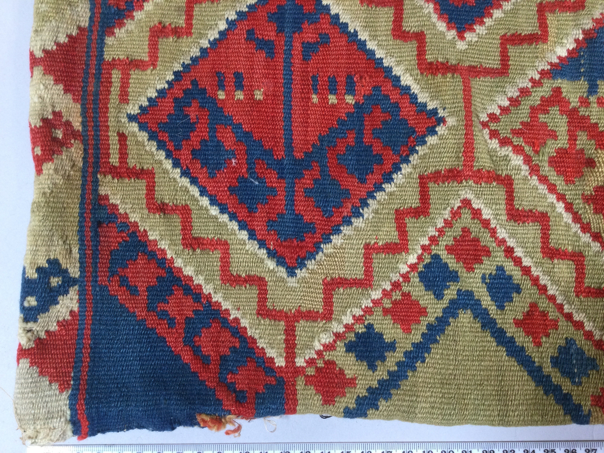 Åkdyna.
Röllakan, ylle på linnevarp, vävt i ett stycke med randig baksida. Trasigt.

Funktion: Komfort och dekoration vid resa
Mycket slitet.