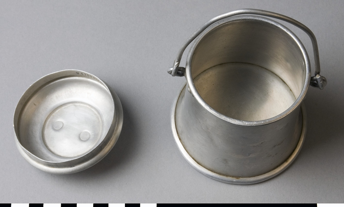 Leksak, mjölkhämtare av aluminium. Behållare (A) med bygelhandtag och lock (B) med ringgrepp.