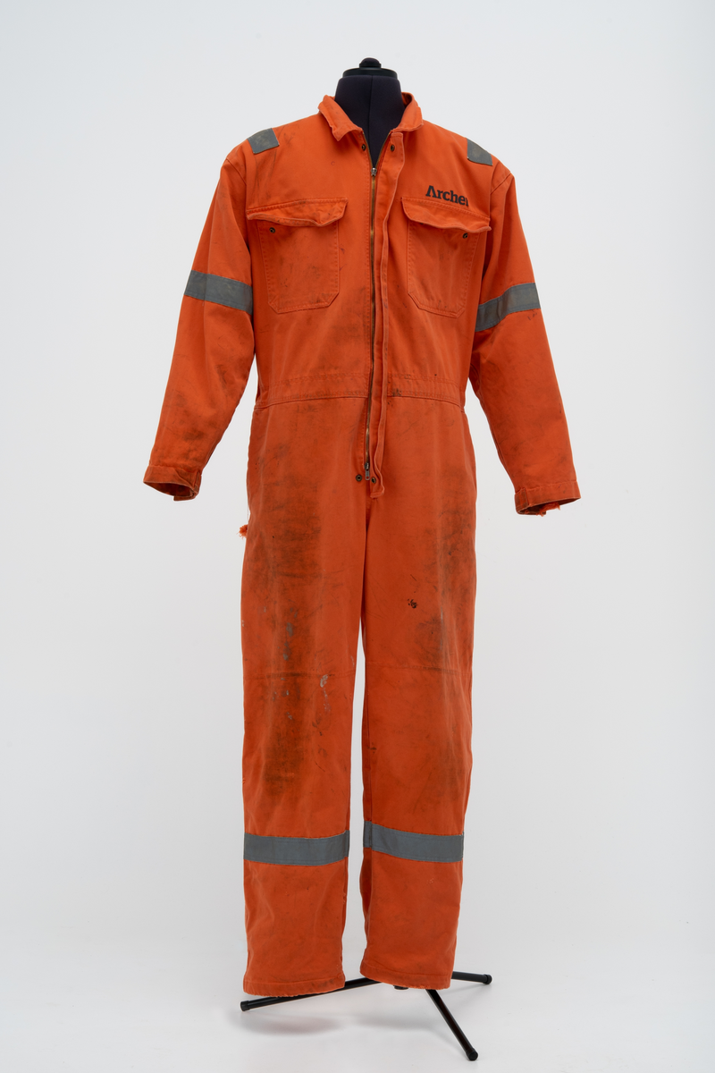 Kjeledress i størrelse 60 med Archer sin logo. Kjeledressen er utstyrt med flere utvendige lommer og reflekser. Innvendig i nakke er det festet en etikett med plattformnavn og QR-kode.