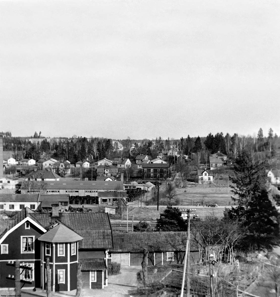 Vy över Väsby från Runbysidan!
Grusåsen längst bak i fotot var på den tiden högre än dagens Scandic Hotell vid Rondellen.
Marieborg till vänster i korsningen Optimusvägen/Kullavägen den hade uppförts 1904 av
metallarbetaren Wiktor Willemansson, fick namn efter hans hustru Maria, och såldes 1917 till AB
Optimus. I huset fanns fyra små vedeldade lägenheter med 1 rum och kök på övervåningen och två
likadana lägenheter och två enkelrum på bottenvåningen. Marieborg var bebott till 1959, och hade
då fått Upplands Väsby kommun som ägare. Det beslutades att Marieborg skulle rivas 1981.
Blombutiken till vänster i korsningen Industrivägen/Kullavägen, Kullavägen som på den tiden även
gick mellan Metallverken och Optimusvägen.
Vita byggnaden till vänster Pettersson’s smedja ägdes av en av bröderna Pettersson som
konkurerade med varandra. På den tiden i Väsby fanns det två smedjor i Väsby den andra låg vid
Väsby Såg.
Huset i förgrunden är Andersberg, som sedan blev ungdomsgården Trubaduren, slutligen
föreningsgård, revs under början av 1990-talet efter en brand. Andersberg byggdes av Anders Mård’s
farmorsfar Karl Erik Ramqvist (1862-1928). Andersberg byggdes cirka 1918 – 1920 några år tidigare
hade han byggt Karlsro, vars staket skymtar till höger, men själva huset är inte med på bilden.
Foto Eric Karlsson