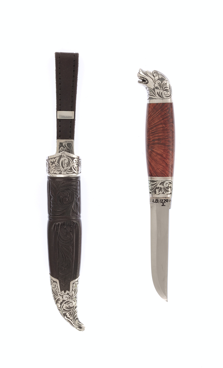 Krok staskniv med sylvholkar. Slira er pauta i svart lær med gravera sylvholkar,Kniven er gravert på hokane med roserankar og har dragehovud med gulltunge som skaftavslutting, Bladet er merkt med AMS.