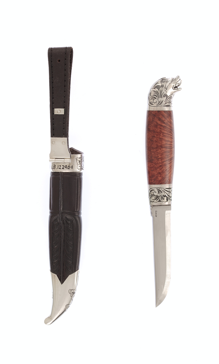 Krok staskniv med sylvholkar. Slira er pauta i svart lær med gravera sylvholkar,Kniven er gravert på hokane med roserankar og har dragehovud med gulltunge som skaftavslutting, Bladet er merkt med AMS.