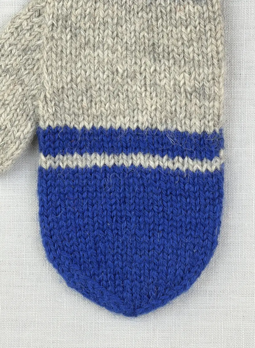 En stickad tumvante, med mudd i 1-1 resår (1 rät och 1 avig maska) och randig vante i slätstickning, av 3-trådigt Sportgarn i ull. Vanten är gjord med kiltumme i ena sidan och avslutas med bandhoptagning i toppen.
Gjord efter Bergå beskrivning D 315 från Bergå Färgeri & Ullspinneri, Stora Skedvi, Dalarna.