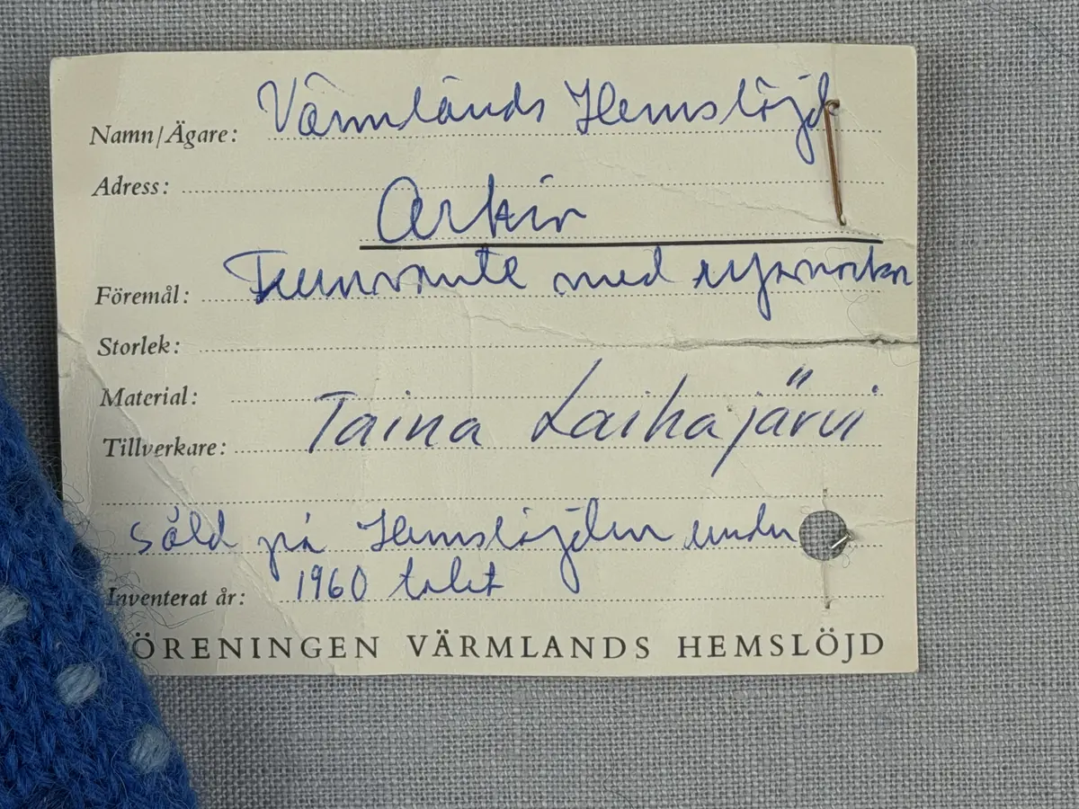 Ett par stickade damvantar, i slätstickning med nockor på vantens insida, av 3-trådigt sportgarn i ull. Nockornas/knutarnas "baksida" bildar ett prickmönster på vantens utsida. 
Vanten har två garntofsar med virkad snodd, kiltumme och är avslutad med bandhoptagning i toppen.