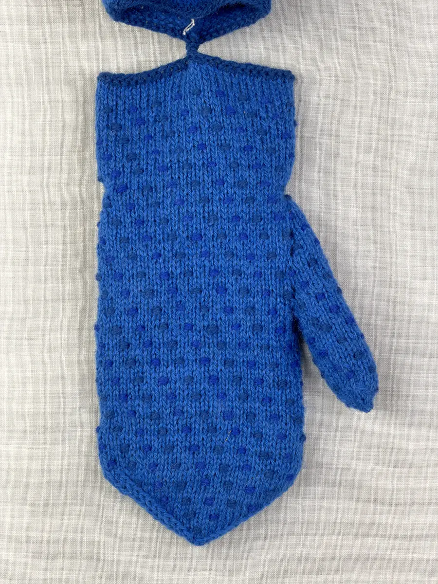 Ett par stickade herrvantar, i slätstickning med nockor på vantens insida, av 3-trådigt sportgarn i ull. Nockornas/knutarnas "baksida" bildar ett prickmönster på vantens utsida. 
Vanten har två garntofsar med virkad snodd, kiltumme i sidan och är avslutad med bandhoptagning i toppen.