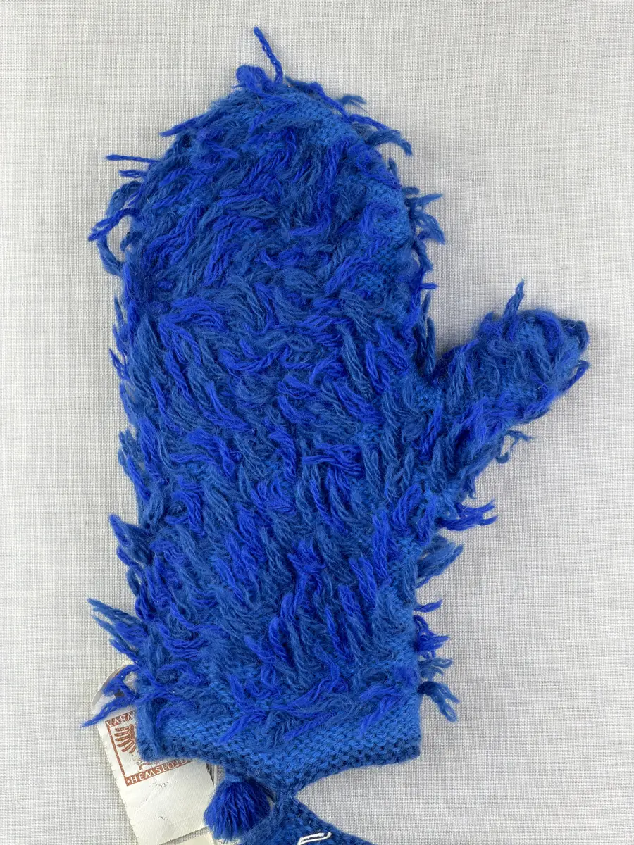 Ett par stickade herrvantar, i slätstickning med nockor på vantens insida, av 3-trådigt sportgarn i ull. Nockornas/knutarnas "baksida" bildar ett prickmönster på vantens utsida. 
Vanten har två garntofsar med virkad snodd, kiltumme i sidan och är avslutad med bandhoptagning i toppen.