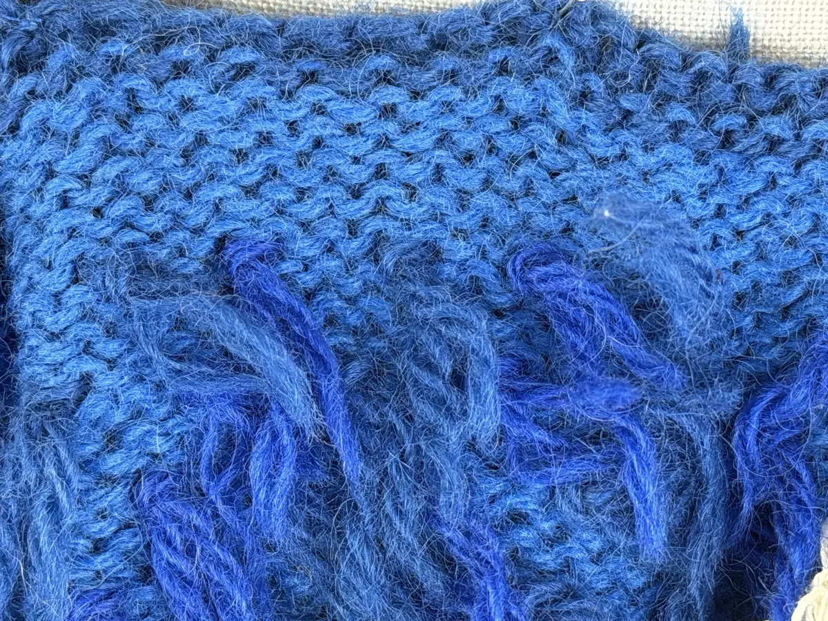 Ett par stickade herrvantar, i slätstickning med nockor på vantens insida, av 3-trådigt sportgarn i ull. Nockornas/knutarnas "baksida" bildar ett prickmönster på vantens utsida. 
Vanten har två garntofsar med virkad snodd, kiltumme i sidan och är avslutad med bandhoptagning i toppen.