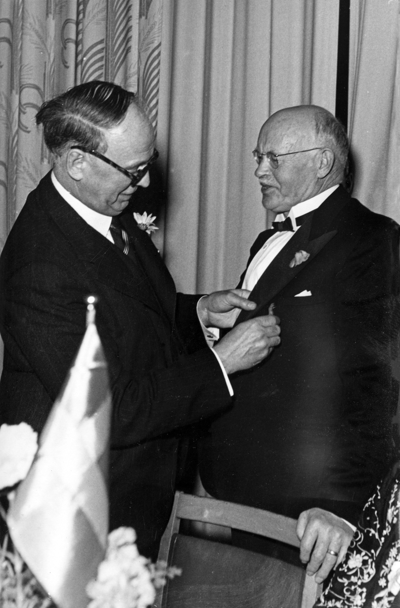 Nynäshamn blir stad. Festbanketten på Nynäs Hotell, nyårsafton 1945. Den kommunala förtroendemannen S. J. Karlsson får motta medaljer av landshövding Levinsson. 

Historisk händelse, nyhet.

Personer på bilden:
Landshövdingen Levinsson och S. J. Karlsson