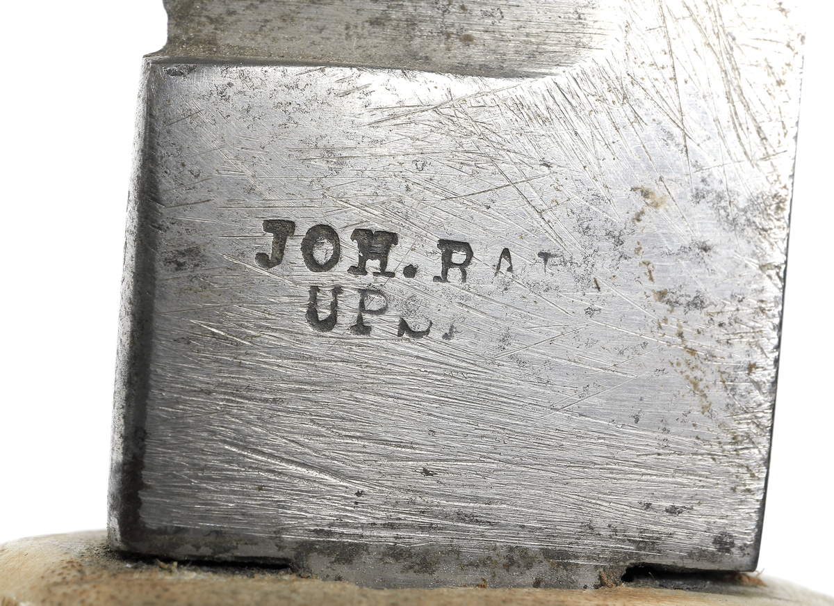 Jaktkniv med dubbelslipad klinga med bred rygg. Klingans spets är något nedböjd. Klingan är stämplad: Joh. Rab. Ups. Skaftet har två urborrningar längst fram vid klingans infästning. Där finns två böjda betar fästa med spetsarna vända framåt. De bildar en enkel parerstång. 
Har brukats som jaktkniv dvs vid styckning av viltet etc., för utdelande av det dödande sticket eller som en ren statussymbol.

Inskrivet i huvudkatalogen 1938.