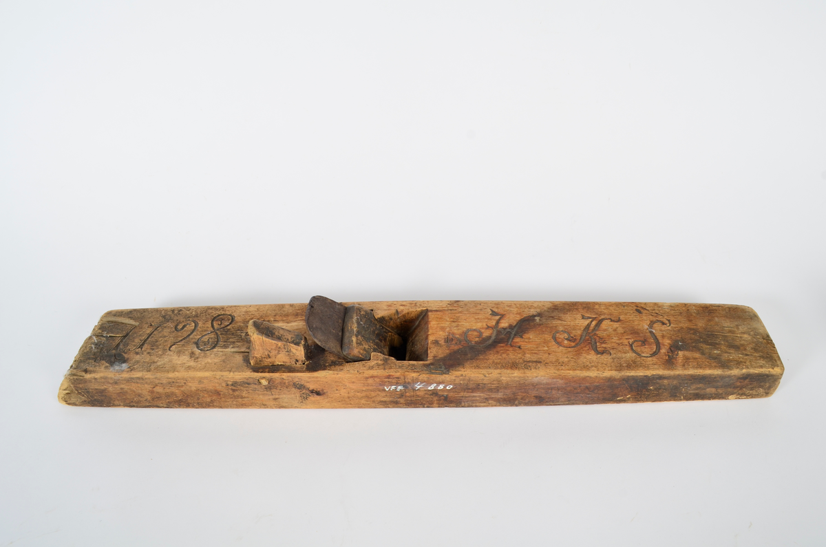 Sponhøvel i bjørk. Utskåren, lite utsprang nederst på bakre del. Nærmest rektangulært hull som smalner nedover med kniv og tretapp til festing, og rom til spon framom. Lite håndtak mot venstre side, lengre bak, festet med trenagle. Innskåret initialer og årstall.