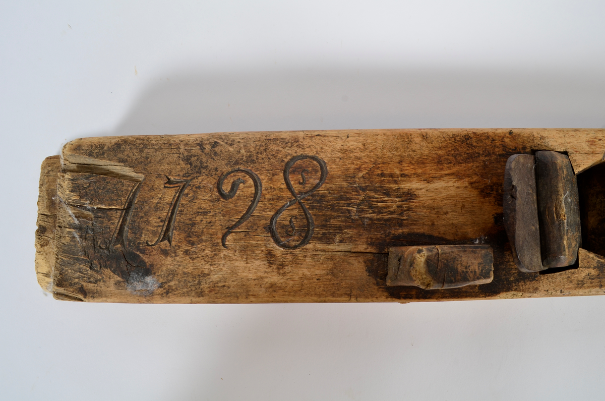 Sponhøvel i bjørk. Utskåren, lite utsprang nederst på bakre del. Nærmest rektangulært hull som smalner nedover med kniv og tretapp til festing, og rom til spon framom. Lite håndtak mot venstre side, lengre bak, festet med trenagle. Innskåret initialer og årstall.