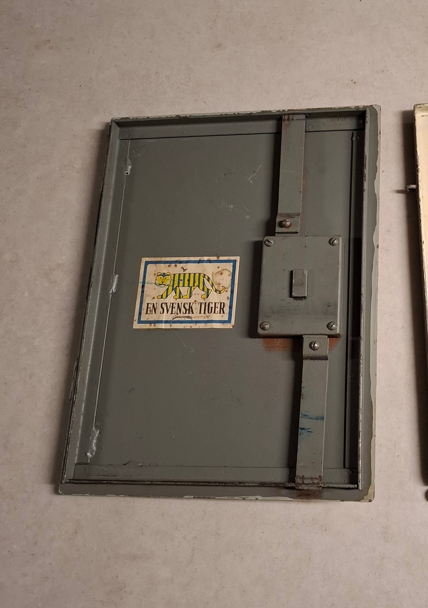 Skåpdörr
På framsidan-   
-En rund påfäst guldig bricka med tre kronor texten "846 ÖVK". 
-En nyckel med bricka på vilket det står "Bb 108 UO-hytt BB". 
-Papperslapp med texten: Skåpsdörr för säkerhetsskåp tillhört Altair T108 SPARAS JB 108 UbBB 951011 M". 

På baksidan - 
-Klistermärke "EN SVENSK TIGER".