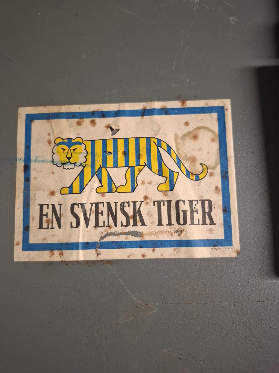 Skåpdörr
På framsidan-   
-En rund påfäst guldig bricka med tre kronor texten "846 ÖVK". 
-En nyckel med bricka på vilket det står "Bb 108 UO-hytt BB". 
-Papperslapp med texten: Skåpsdörr för säkerhetsskåp tillhört Altair T108 SPARAS JB 108 UbBB 951011 M". 

På baksidan - 
-Klistermärke "EN SVENSK TIGER".