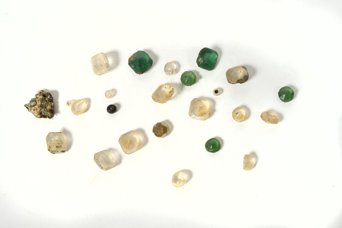 Smyckesstenar av glas. Både lösa och infattade i metall. Gröna och transperenta.
