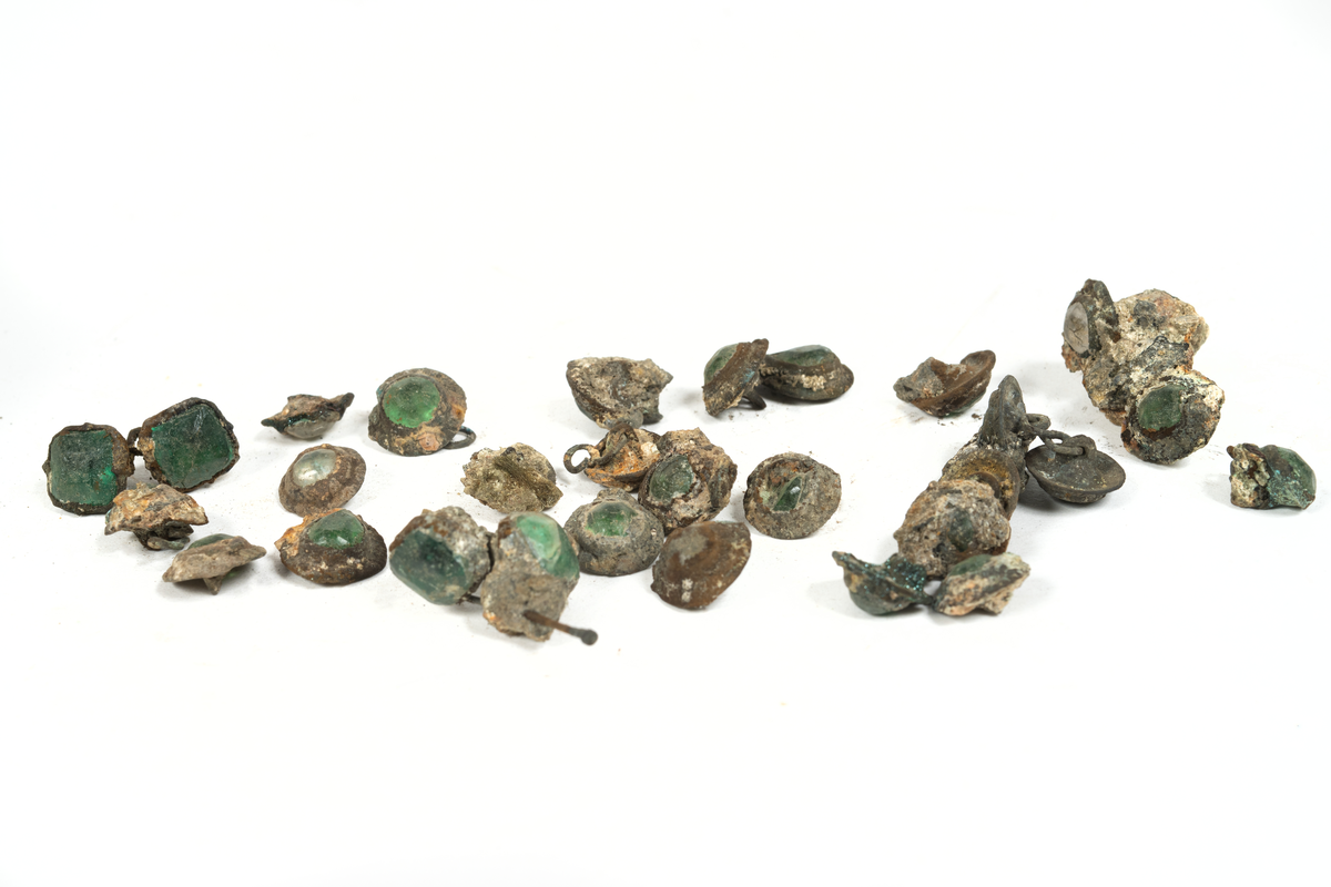 Smyckesstenar av glas. Både lösa och infattade i metall. Gröna och transperenta.