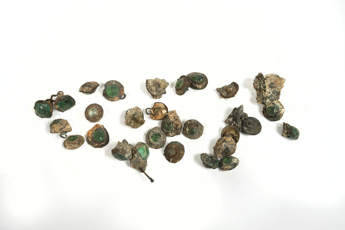 Smyckesstenar av glas. Både lösa och infattade i metall. Gröna och transperenta.