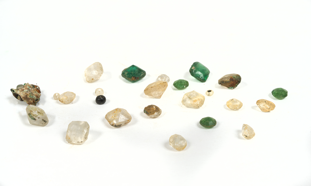 Smyckesstenar av glas. Både lösa och infattade i metall. Gröna och transperenta.