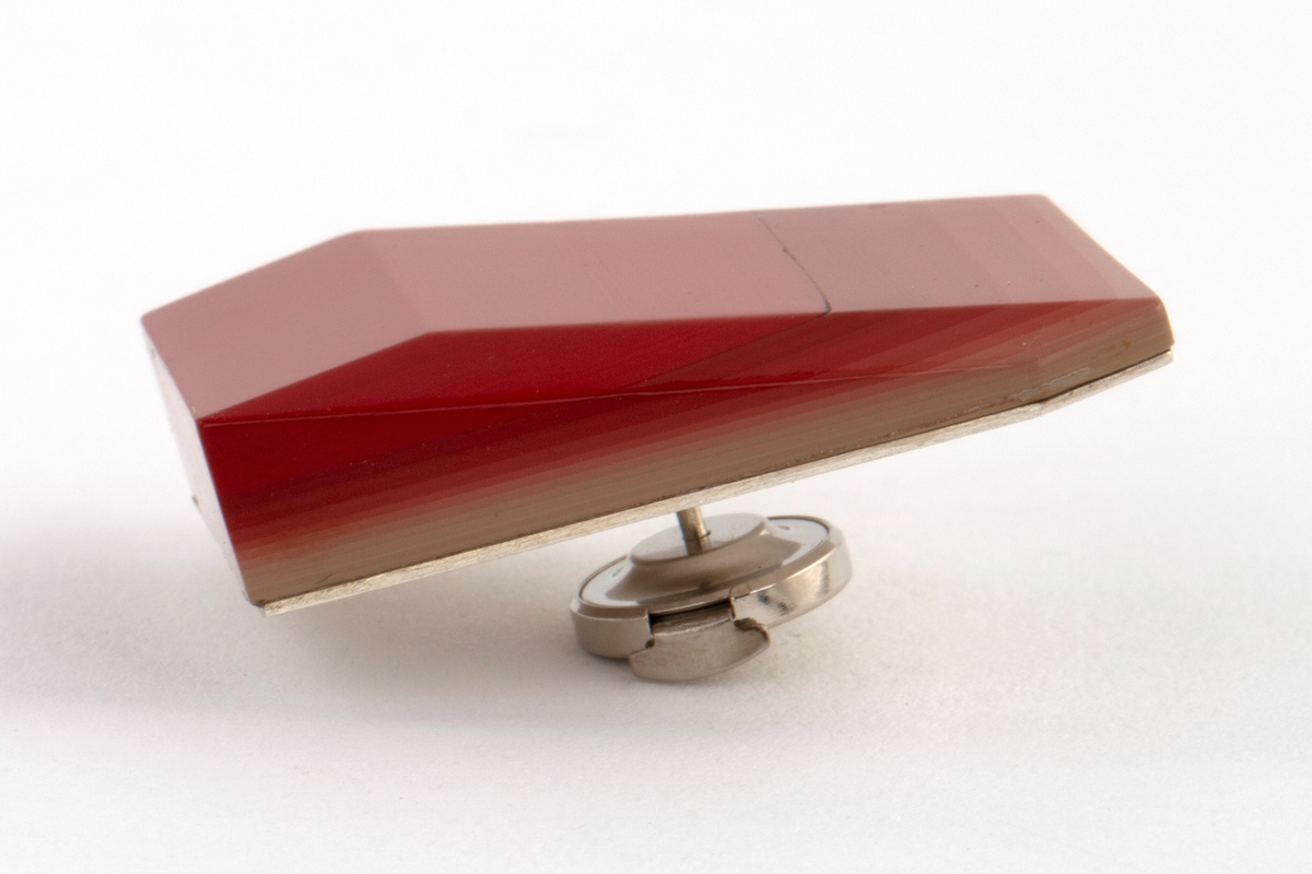 Brosje lagd av Urushi-lakk med teknikken cho-shitsu. 3 mm tykke lag lakt 100 ganger. Overgangen mellom lagene synes i fargene på lakken. Brosjen kan sies å være todelt. Nederste del kan sees som en base der fargene på lakklagene går fra lys gulbeige til mørk rød. Den øverste delen er monokrom rød. Brosjen har syv kanter og skaper en tredimensjonal effekt. Lakken er montert på en sølvplate med pin.