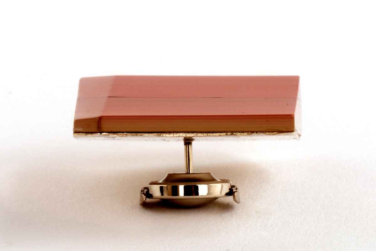 Brosje lagd av Urushi-lakk med teknikken cho-shitsu. 3 mm tykke lag lakt 100 ganger. Overgangen mellom lagene synes i fargene på lakken. Brosjen kan sies å være todelt. Nederste del kan sees som en base der fargene på lakklagene går fra lys gulbeige til mørk rød. Den øverste delen er monokrom rød. Brosjen har syv kanter og skaper en tredimensjonal effekt. Lakken er montert på en sølvplate med pin.