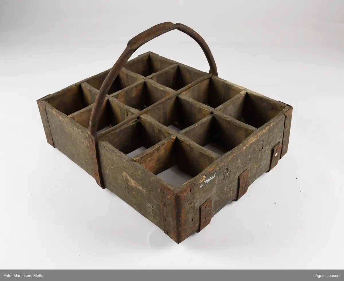 Trekasse med rom for tolv flasker. Jernhåndtak og jernbeslag i hjørnene og under. På langsiden er det brennmerket inn "MRIEF"
