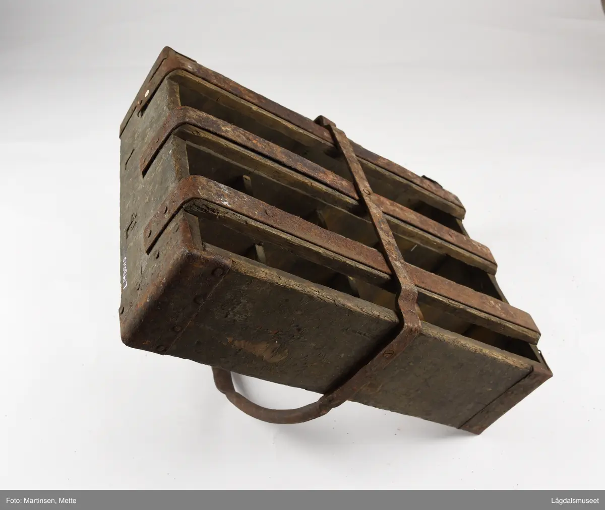 Trekasse med rom for tolv flasker. Jernhåndtak og jernbeslag i hjørnene og under. På langsiden er det brennmerket inn "MRIEF"