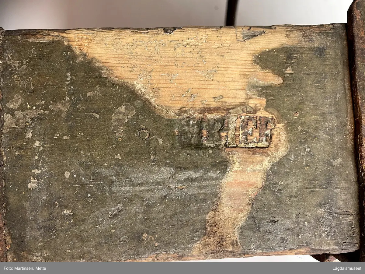 Trekasse med rom for tolv flasker. Jernhåndtak og jernbeslag i hjørnene og under. På langsiden er det brennmerket inn "MRIEF"