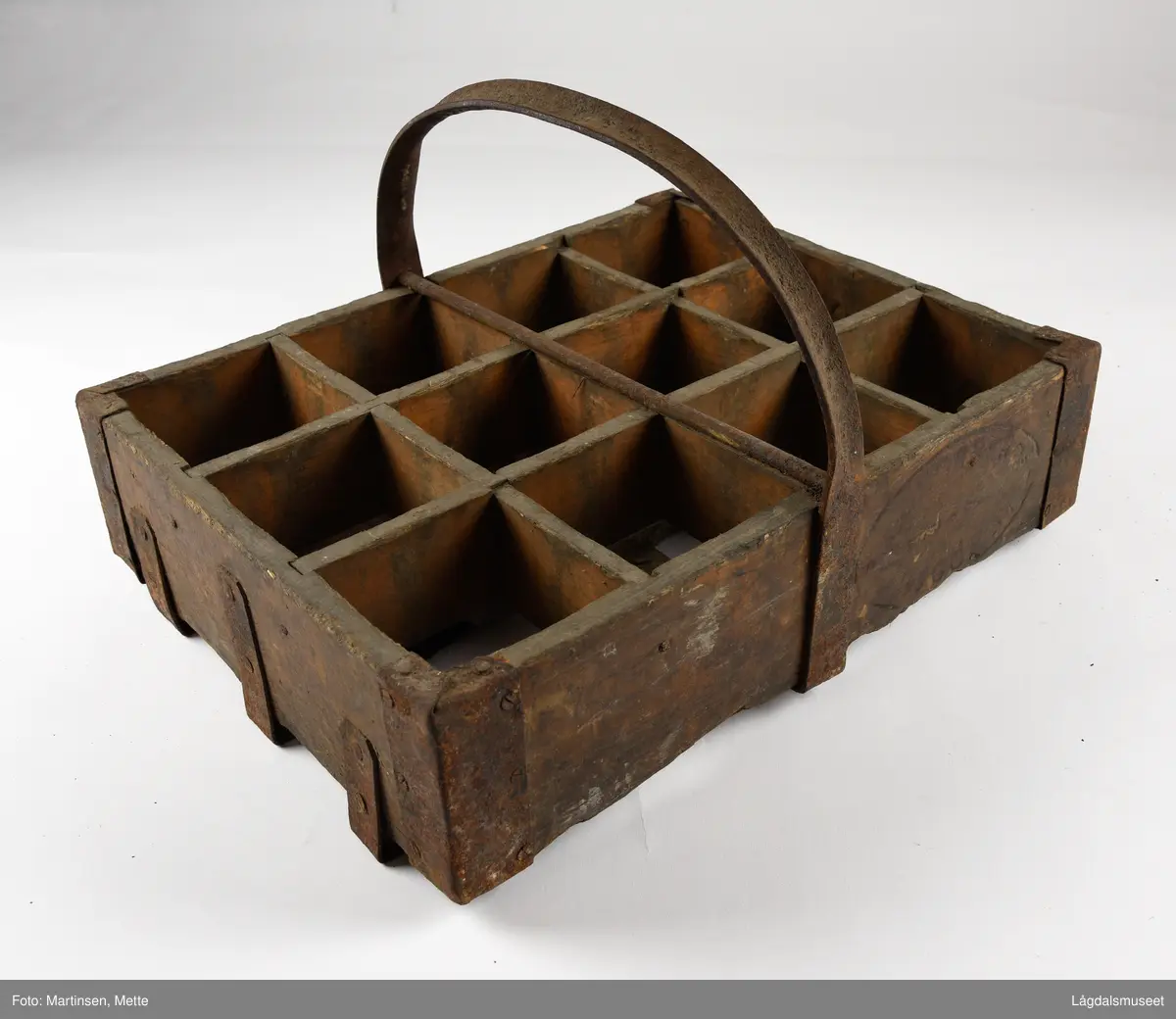 Trekasse med rom for tolv flasker. Jernhåndtak og jernbeslag i hjørnene og under. På begge langsidene er det brennmerket inn "KONGSBERG BRYGGERI"