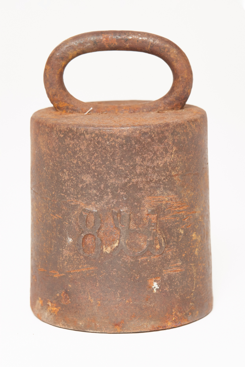 Et svart vektlodd, rundt, videst nederst, håndtak på toppen, tekst på loddet 8 Lb, gotisk skrift