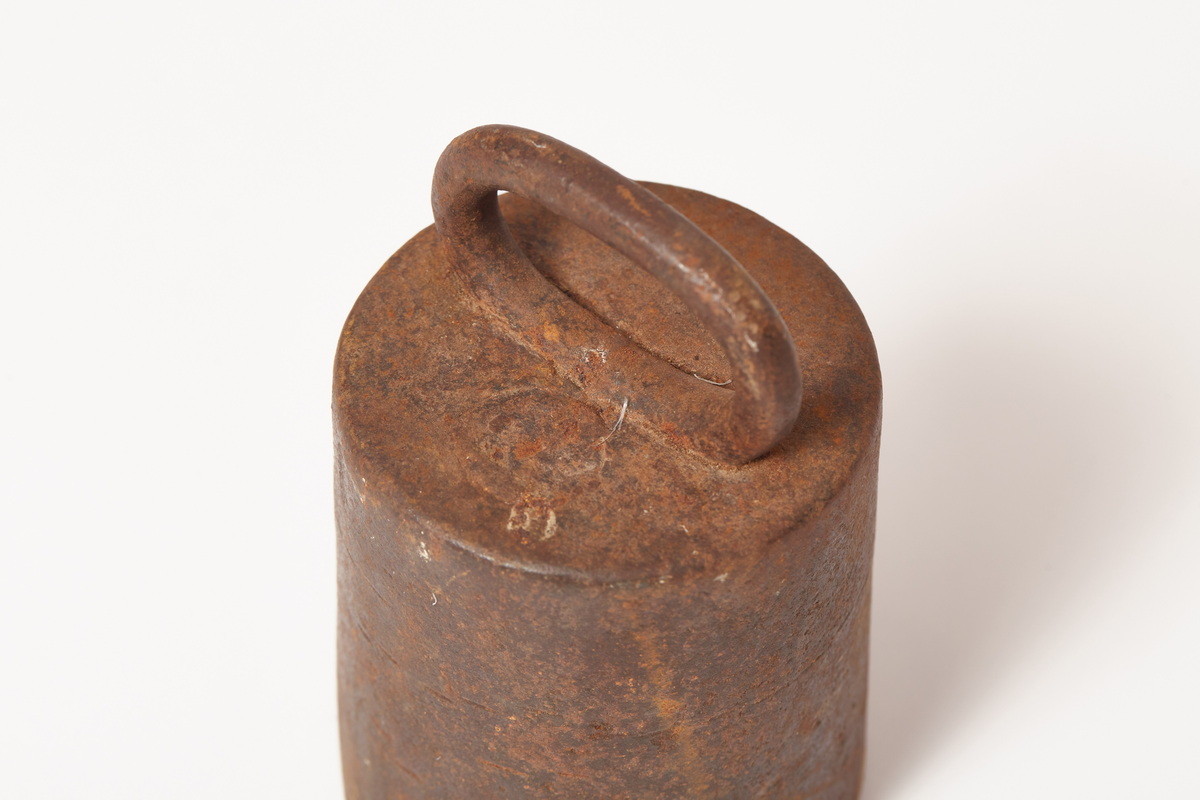 Et svart vektlodd, rundt, videst nederst, håndtak på toppen, tekst på loddet 8 Lb, gotisk skrift