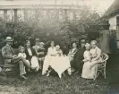 Ett okänt sällskap har slagit sig ner i en trädgård för att dricka kaffe m.m. Längst till höger syns fröken Gertrud Eksandh, Växjö, 
Torekov (?), Falkenberg (?).