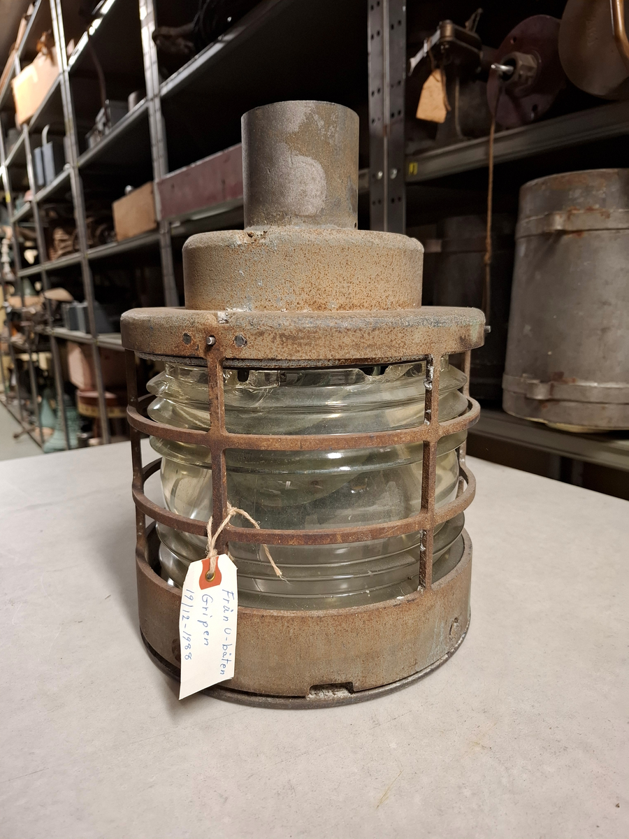 Lanterna i stål och glas. Cylinderformad. Lapp med texten: "Från u-båten Gripen 19/12-1988". Delar av glaset är krossat, väldigt rostig.
