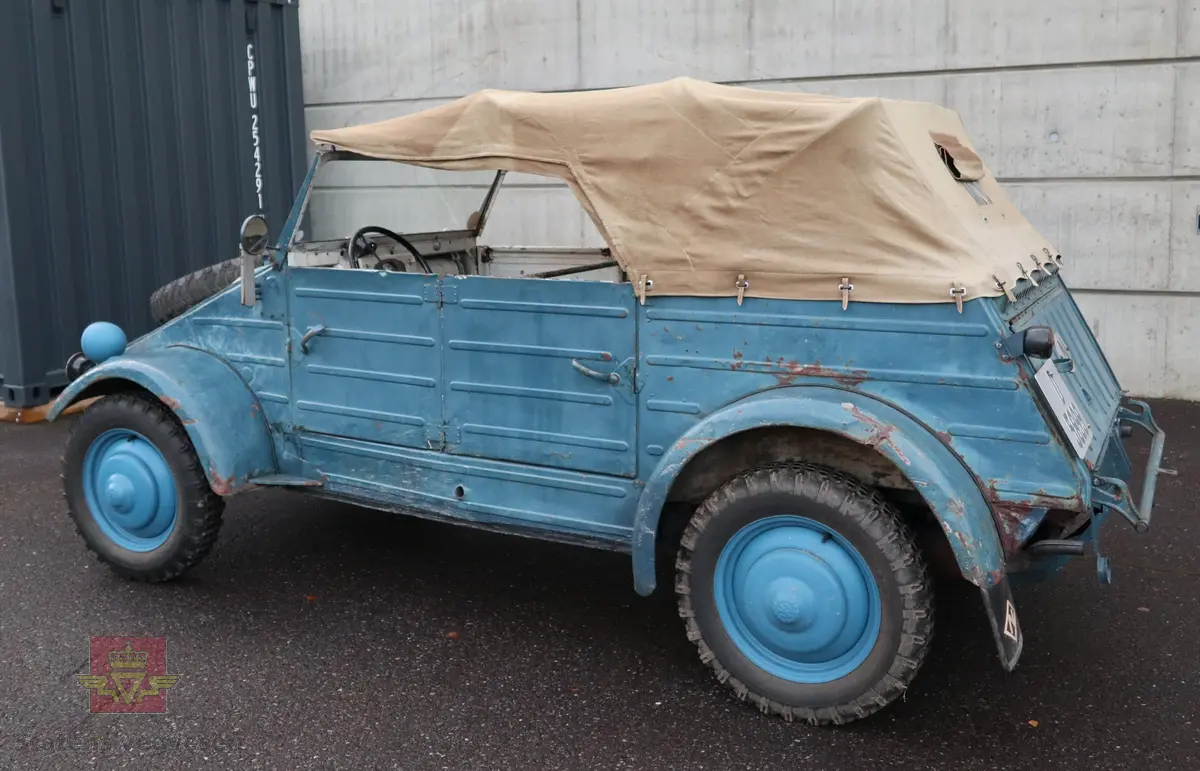 Volkswagen Typ 82 Kübelwagen. Åpen (med kalesje). Blå utvendig og hvit innvendig. Opprinnelig har hele bilen vært sandfarget. Man kan også se rester av grønn farge under det blå. Svart motorrom. Bilen har fire hjul og er toakslet med trekk på bakre. Bensindrevet firesylindret firetakts motor med et sylindervolum på 1192 cm3 og en effekt på 31 hk - 23 kW. Motoren har forgasser, er luftavkjølt, og sitter bak på bilen. 4-trinns manuell girkasse med spak i gulvet. Antall sitteplasser var tre ettersom dette opprinnelig er en radiobil, men nå har bilen sofa bak som tilsier fire sitteplasser totalt. Original dekkdimensjon rundt om skal være 5.00 x 16. Bilen har innvendig gulv av tre, dette er ikke det originale. Frontruta er sprekt. Kilometerstand på instrumentet viser 28084 km.