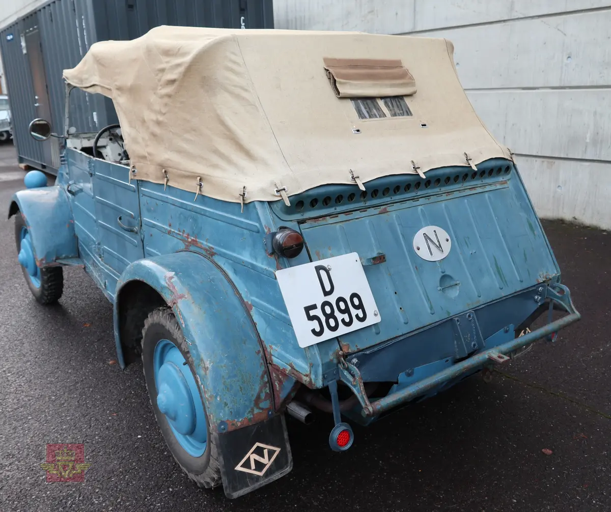 Volkswagen Typ 82 Kübelwagen. Åpen (med kalesje). Blå utvendig og hvit innvendig. Opprinnelig har hele bilen vært sandfarget. Man kan også se rester av grønn farge under det blå. Svart motorrom. Bilen har fire hjul og er toakslet med trekk på bakre. Bensindrevet firesylindret firetakts motor med et sylindervolum på 1192 cm3 og en effekt på 31 hk - 23 kW. Motoren har forgasser, er luftavkjølt, og sitter bak på bilen. 4-trinns manuell girkasse med spak i gulvet. Antall sitteplasser var tre ettersom dette opprinnelig er en radiobil, men nå har bilen sofa bak som tilsier fire sitteplasser totalt. Original dekkdimensjon rundt om skal være 5.00 x 16. Bilen har innvendig gulv av tre, dette er ikke det originale. Frontruta er sprekt. Kilometerstand på instrumentet viser 28084 km.