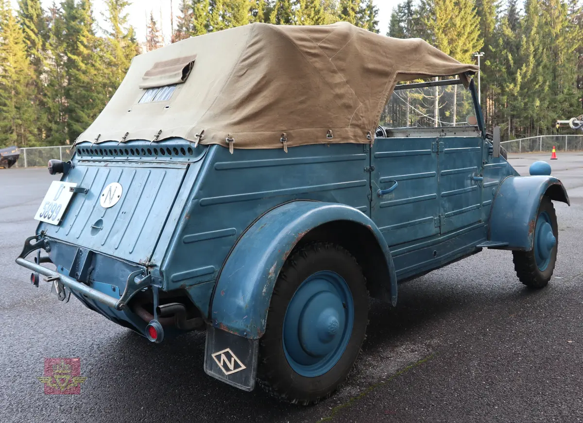 Volkswagen Typ 82 Kübelwagen. Åpen (med kalesje). Blå utvendig og hvit innvendig. Opprinnelig har hele bilen vært sandfarget. Man kan også se rester av grønn farge under det blå. Svart motorrom. Bilen har fire hjul og er toakslet med trekk på bakre. Bensindrevet firesylindret firetakts motor med et sylindervolum på 1192 cm3 og en effekt på 31 hk - 23 kW. Motoren har forgasser, er luftavkjølt, og sitter bak på bilen. 4-trinns manuell girkasse med spak i gulvet. Antall sitteplasser var tre ettersom dette opprinnelig er en radiobil, men nå har bilen sofa bak som tilsier fire sitteplasser totalt. Original dekkdimensjon rundt om skal være 5.00 x 16. Bilen har innvendig gulv av tre, dette er ikke det originale. Frontruta er sprekt. Kilometerstand på instrumentet viser 28084 km.