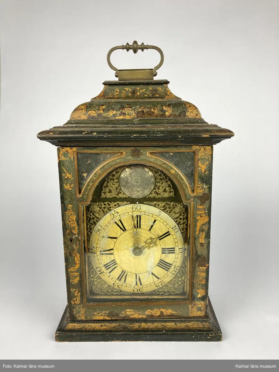 KLM 2269. Bordsur. Fodral av trä, lackerat i grönt med målade kinesiska figurer och landskap i svart och guld. Upptill handtag av mässing. Samtliga sidor är försedda med glaspartier och upptill mindre rutor med spegelglas. Både baksida och framsida kan öppnas. Vitmålad urtavla omgiven av bronsornament. Urverket av mässing och stål med rik ornering. Urverket är signerat: Hans Strehl 1637. Fodralet saknar fötter samt knoppar som suttit på ovansidan.