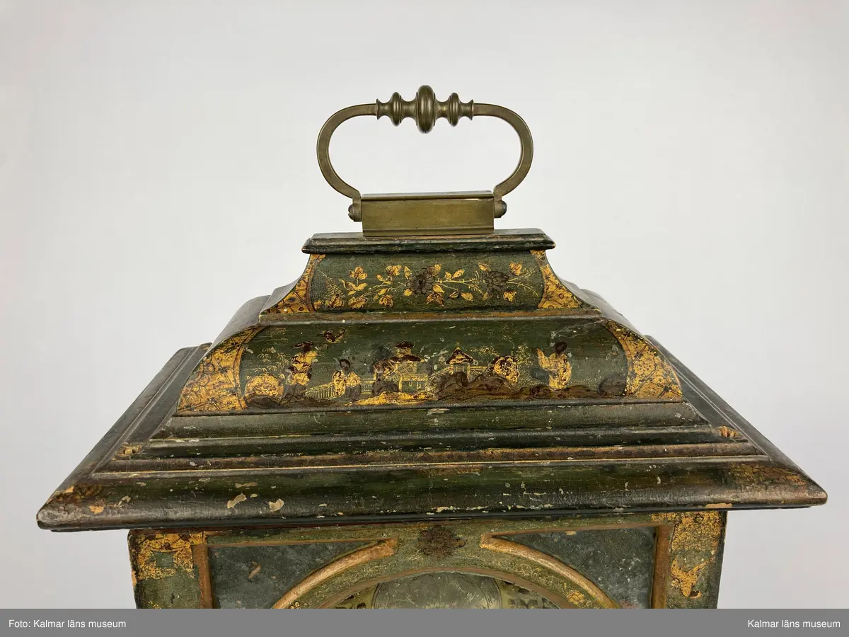 KLM 2269. Bordsur. Fodral av trä, lackerat i grönt med målade kinesiska figurer och landskap i svart och guld. Upptill handtag av mässing. Samtliga sidor är försedda med glaspartier och upptill mindre rutor med spegelglas. Både baksida och framsida kan öppnas. Vitmålad urtavla omgiven av bronsornament. Urverket av mässing och stål med rik ornering. Urverket är signerat: Hans Strehl 1637. Fodralet saknar fötter samt knoppar som suttit på ovansidan.