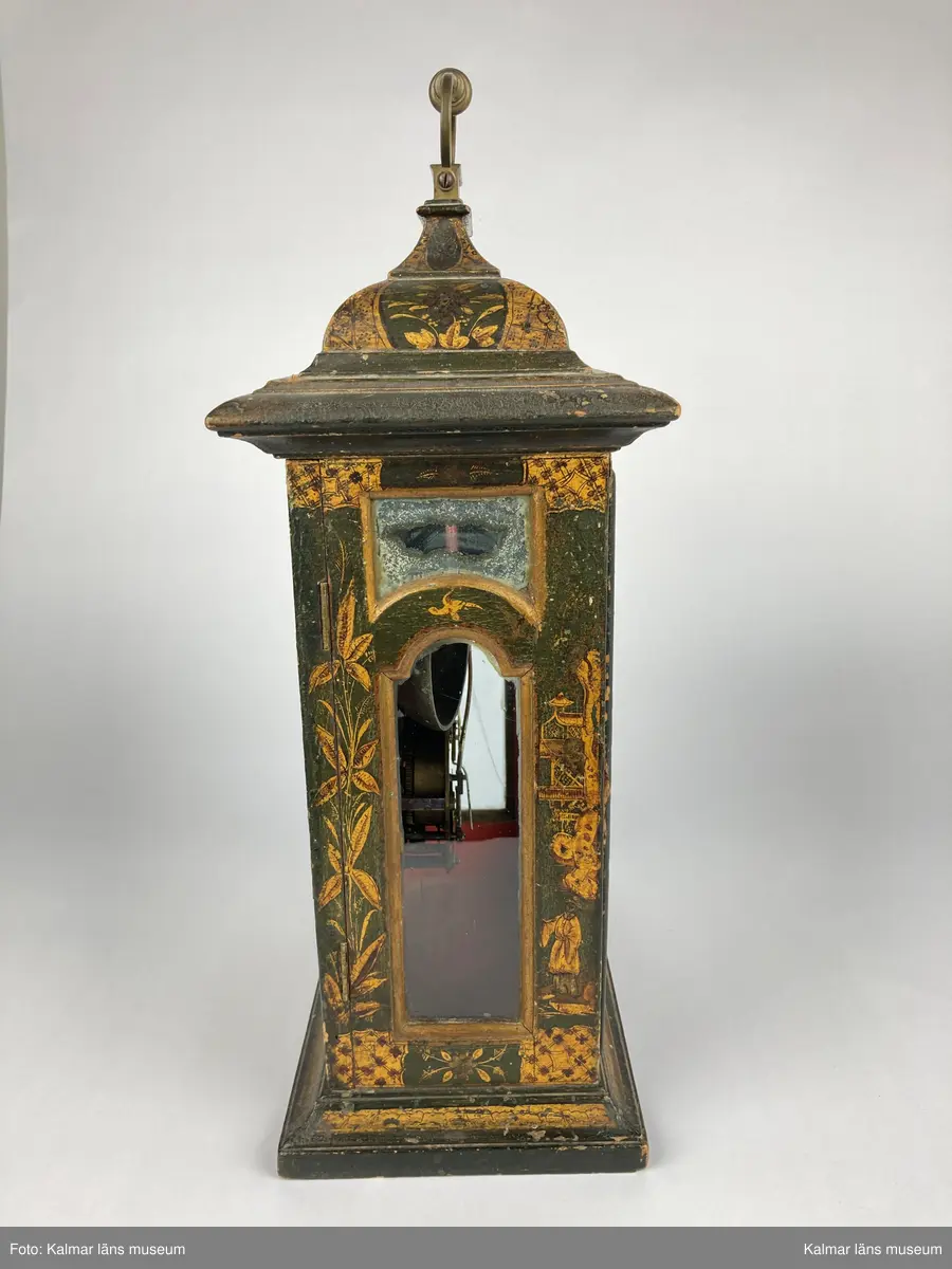 KLM 2269. Bordsur. Fodral av trä, lackerat i grönt med målade kinesiska figurer och landskap i svart och guld. Upptill handtag av mässing. Samtliga sidor är försedda med glaspartier och upptill mindre rutor med spegelglas. Både baksida och framsida kan öppnas. Vitmålad urtavla omgiven av bronsornament. Urverket av mässing och stål med rik ornering. Urverket är signerat: Hans Strehl 1637. Fodralet saknar fötter samt knoppar som suttit på ovansidan.