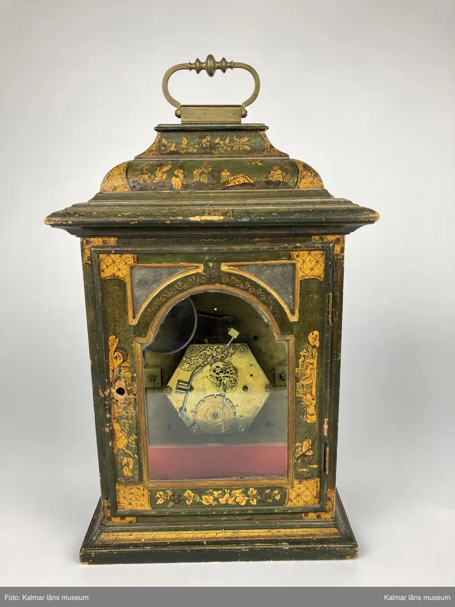KLM 2269. Bordsur. Fodral av trä, lackerat i grönt med målade kinesiska figurer och landskap i svart och guld. Upptill handtag av mässing. Samtliga sidor är försedda med glaspartier och upptill mindre rutor med spegelglas. Både baksida och framsida kan öppnas. Vitmålad urtavla omgiven av bronsornament. Urverket av mässing och stål med rik ornering. Urverket är signerat: Hans Strehl 1637. Fodralet saknar fötter samt knoppar som suttit på ovansidan.