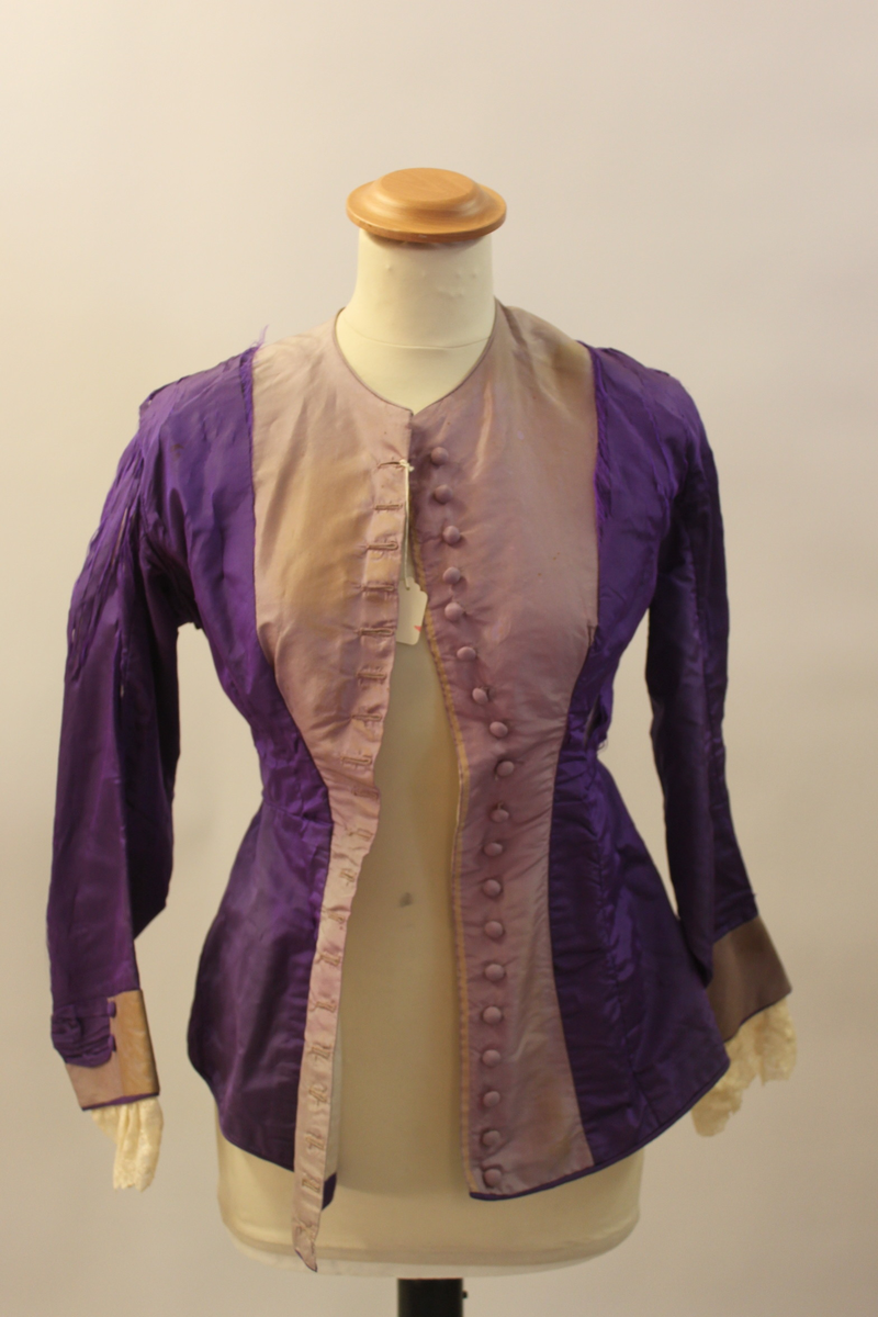 Klänningsjacka i siden med klädda knappar och spetsar i ärmsluten.