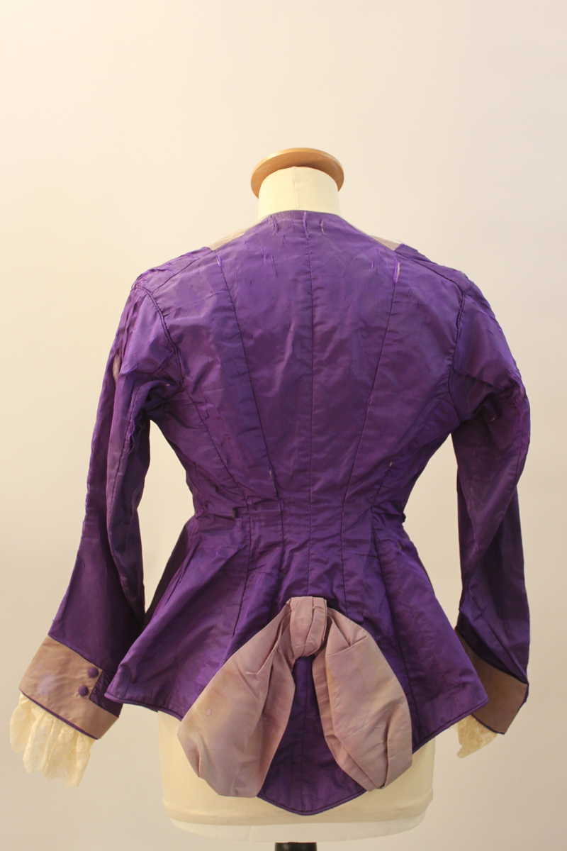 Klänningsjacka i siden med klädda knappar och spetsar i ärmsluten.