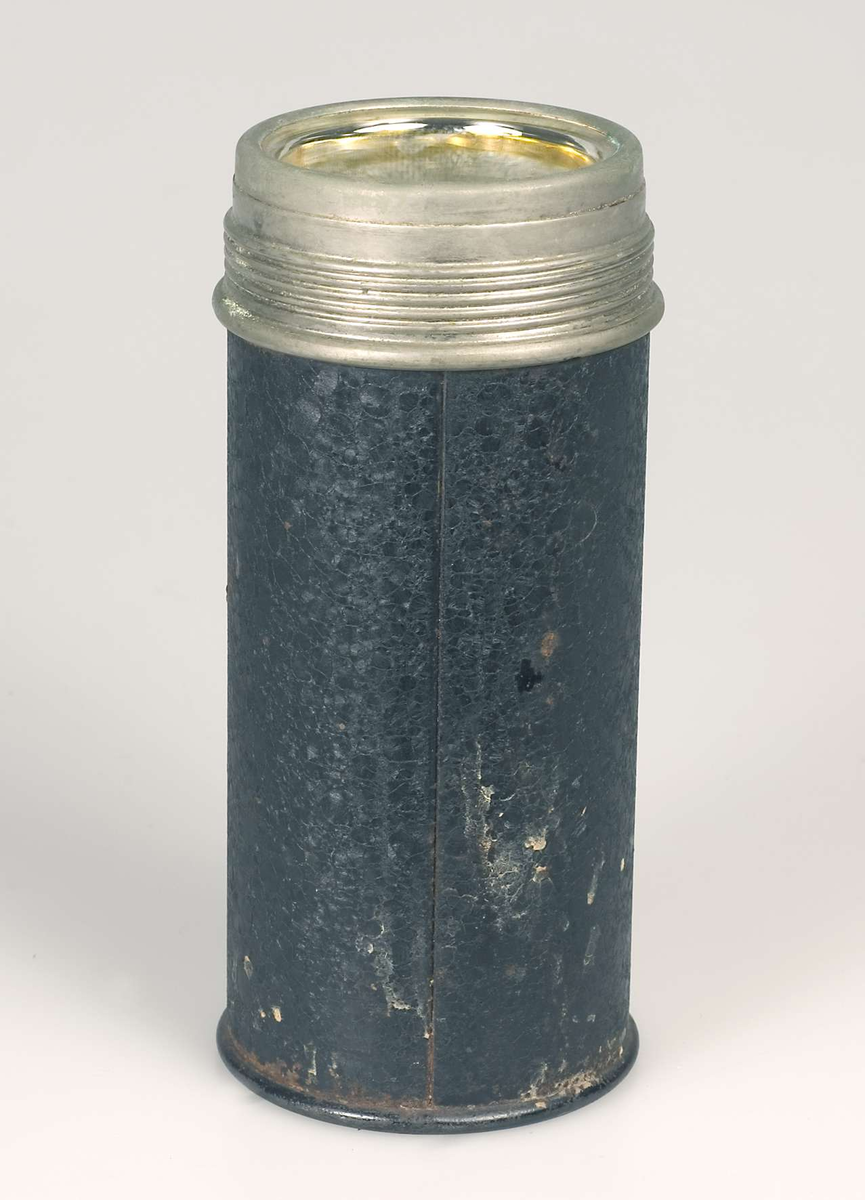 Termos av svartlackerad och förnicklad plåt. Invändig termosflaska av kvicksilverglas. Vid mynning. Kork med förnicklad metallöverdel. Lock i form av vid mugg som skruvas på. Märkt: ORIGINAL THERMOS D.R.W.Z.
Oxiderad.

