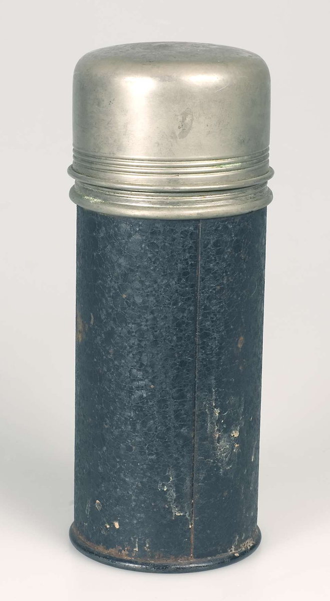 Termos av svartlackerad och förnicklad plåt. Invändig termosflaska av kvicksilverglas. Vid mynning. Kork med förnicklad metallöverdel. Lock i form av vid mugg som skruvas på. Märkt: ORIGINAL THERMOS D.R.W.Z.
Oxiderad.

