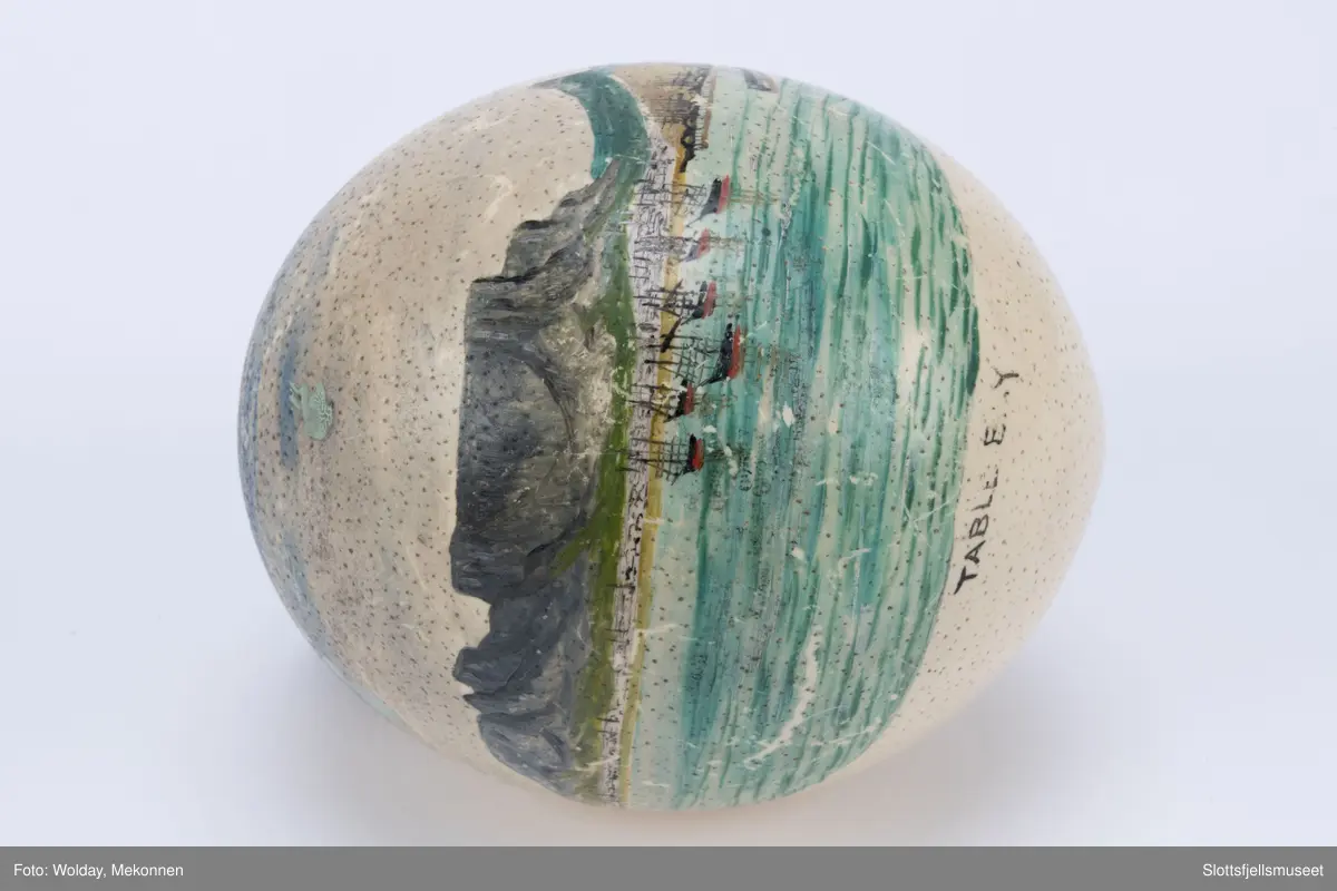 Strutseegg dekorert med unionsflagg på den ene side og et bilde fra havnen i Cape Town med Table Mountain på den andre side. Under bildet står det "TABLE E.Y."