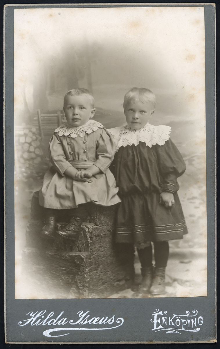 Visitkort/ ateljéfoto av två okända barn. Fotograferat i Hilda Isaeus ateljé på Eriksgatan, Enköping.